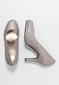 Zapatos de tacón alto rosa brillantes con un interior suave, punta redondeada y un delgado tacón stilettos. Presenta una suela negra para ofrecer tracción.
