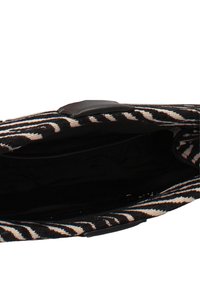 Pochette à motif zèbre noir et blanc ouverte, montrant un intérieur vide avec un doublure noire et un petit rabat de fermeture.