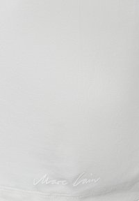 Weißer Stoff mit subtiler gerippter Textur und gesäumtem Saum, mit einem kleinen, kursive weißen Logotext nahe dem unteren Rand.