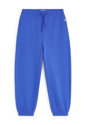 Pantalon de survêtement bleu à taille élastique avec cordon de serrage et poignets élastiques, doté de poches latérales et d'une petite étiquette de marque sur le côté droit.