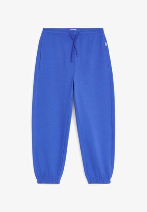 Pantalon de survêtement bleu à taille élastique avec cordon de serrage et poignets élastiques, doté de poches latérales et d'une petite étiquette de marque sur le côté droit.