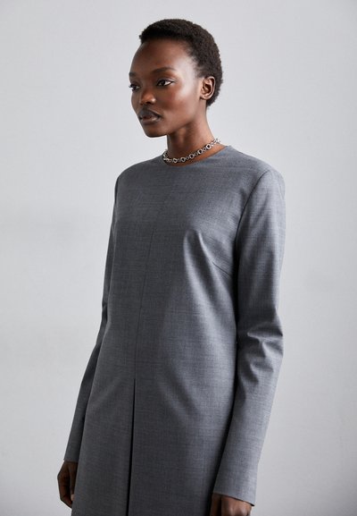 Vestido gris de manga larga con corte recto, tejido texturizado y una sutil costura vertical. Presenta un escote redondeado y un pliegue en la parte frontal.