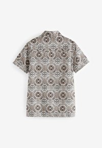 Camisa de manga corta en tejido ligero con un detallado patrón floral y circular multicolor sobre un fondo beige.