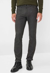 Donkergrijze broek van een gestructureerd materiaal, slim fit ontwerp met opgerolde boorden, gecombineerd met zwarte dresschoenen.