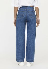 Pantalones vaqueros de pierna ancha en denim, con dos bolsillos traseros con costura decorativa, terminados con una cintura alta y dobladillos enrollados.
