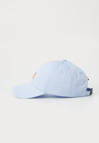 Căciulă bleu deschis cu o vizieră curbată, curea ajustabilă și detalii cu logo portocaliu pe față, fabricată dintr-un material durabil.