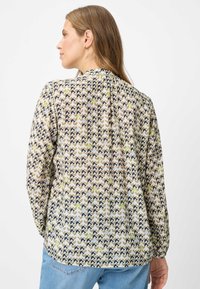 Blouse met lange mouwen van lichtgewicht, beige stof met een patroon van golvende lijnen in marineblauw, groen en bruin. Achterkant met geplooide details.