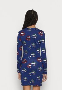 Long-sleeve, fitted dress in blue fabric featuring a pattern of colorful lips with glitter accents. Smooth texture, knee-length design.