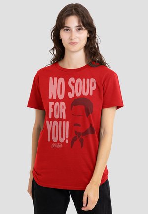 Young woman wearing a red t-shirt with bold text "NO SOUP FOR YOU!" and a stylized man’s face graphic from Seinfeld.