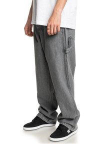 Storede mørkegrå jeans lavet af denim med en blød tekstur, der har sidelommer og opfoldede manchetter, parret med sorte sneakers.