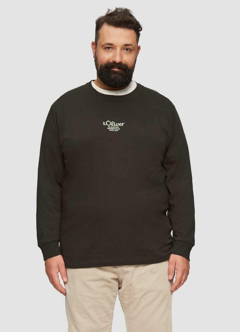 Dunkelbrauner Sweatshirt mit langen Ärmeln und Rundhalsausschnitt, mit weißem gesticktem Logo. Getragen mit beigen Cordhosen.