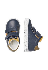 Marineblaue Leder-Sneaker mit Klettverschlüssen, weiß gesprenkeltem Sohlenrand, hellbraunen Akzenten und durchlochtem Detail an den Seiten.