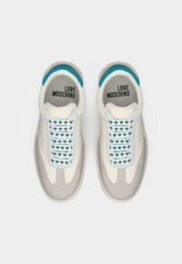 Λευκά και μπεζ sneakers Love Moschino με κορδόνια σε σχέδιο καρδιών σε τιρκουάζ και τιρκουάζ λεπτομέρειες, εμφανιζόμενα από επάνω προς τα κάτω.