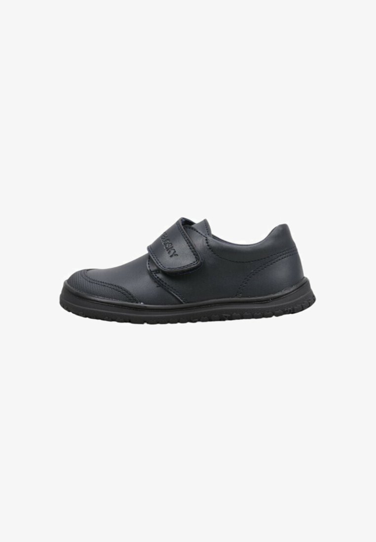 Chaussure noire à profil bas avec un bout arrondi, une semelle texturée et une large bande velcro sur le dessus pour un ajustement facile.