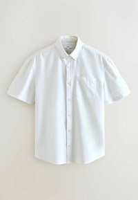 Chemise blanche à manches courtes avec poche avant et col boutonné, présentée à plat sur un fond clair.