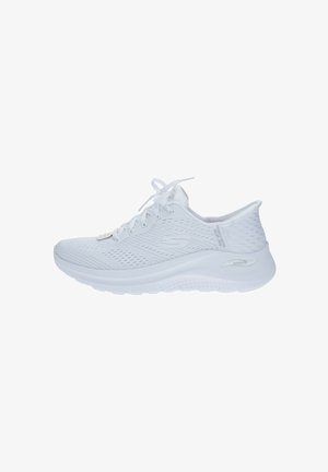 Chaussure de sport blanche avec une tige en mesh respirant, un design texturé, des lacets plats et une semelle rembourrée arborant un logo discret sur le côté.