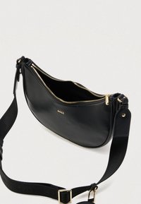 Fekete bőr keresztpántos táska aranyszínű cipzárral és "BOSS" logóval, állítható fekete szövetpánttal és egy kis csatolt zsebbel.