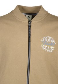 Giacca beige zip-up realizzata in tessuto morbido, con colletto alto, cerniera a righe blu navy e logo stampato in accenti bianchi e blu.