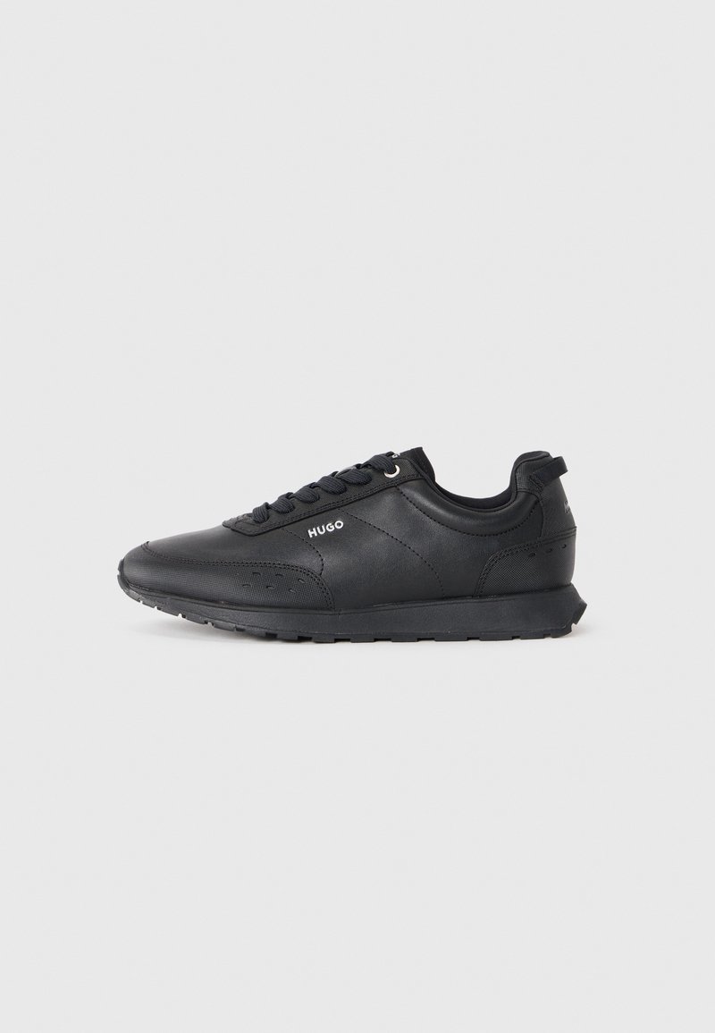Black low-top sneaker with lace-up front, textured details, and "HUGO" logo on side, shown in profile on white background.