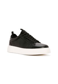 Sneaker nera in pelle con finitura liscia, punta rotonda e design con lacci. Presenta una suola in gomma bianca e dettagli di cucitura sottili.