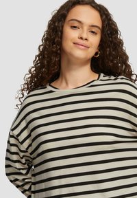 Gestreepte lange mouwen shirt, met afwisselend zwarte en beige strepen, relaxte pasvorm, brede ronde hals, zachte stof en casual ontwerp.