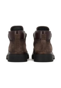 Botine din suede maro până la glezne cu accente din piele maronie închisă, suprafețe texturate, vârfuri rotunjite și tălpi din cauciuc cu striații orizontale.