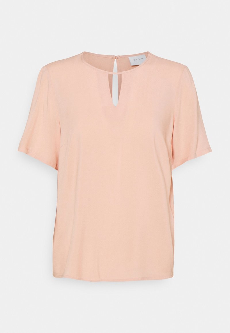 Blouse pêche claire à manches courtes avec un col rond présentant une petite ouverture en forme de trou de serrure à l'avant et une fermeture à bouton dans le dos.