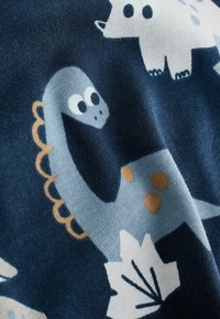 Tissu bleu avec des illustrations amusantes de dinosaures, incluant un dinosaure à long cou bleu clair avec des taches orange et des feuilles blanches.