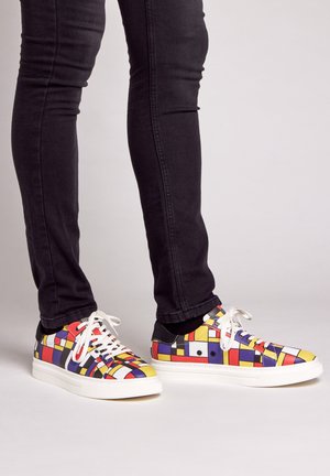 Kleurige lage sneakers met een geometrisch patroon in rood, geel, blauw en zwarte accenten. Rubberen zool; witte veters; gladde oppervlakte.