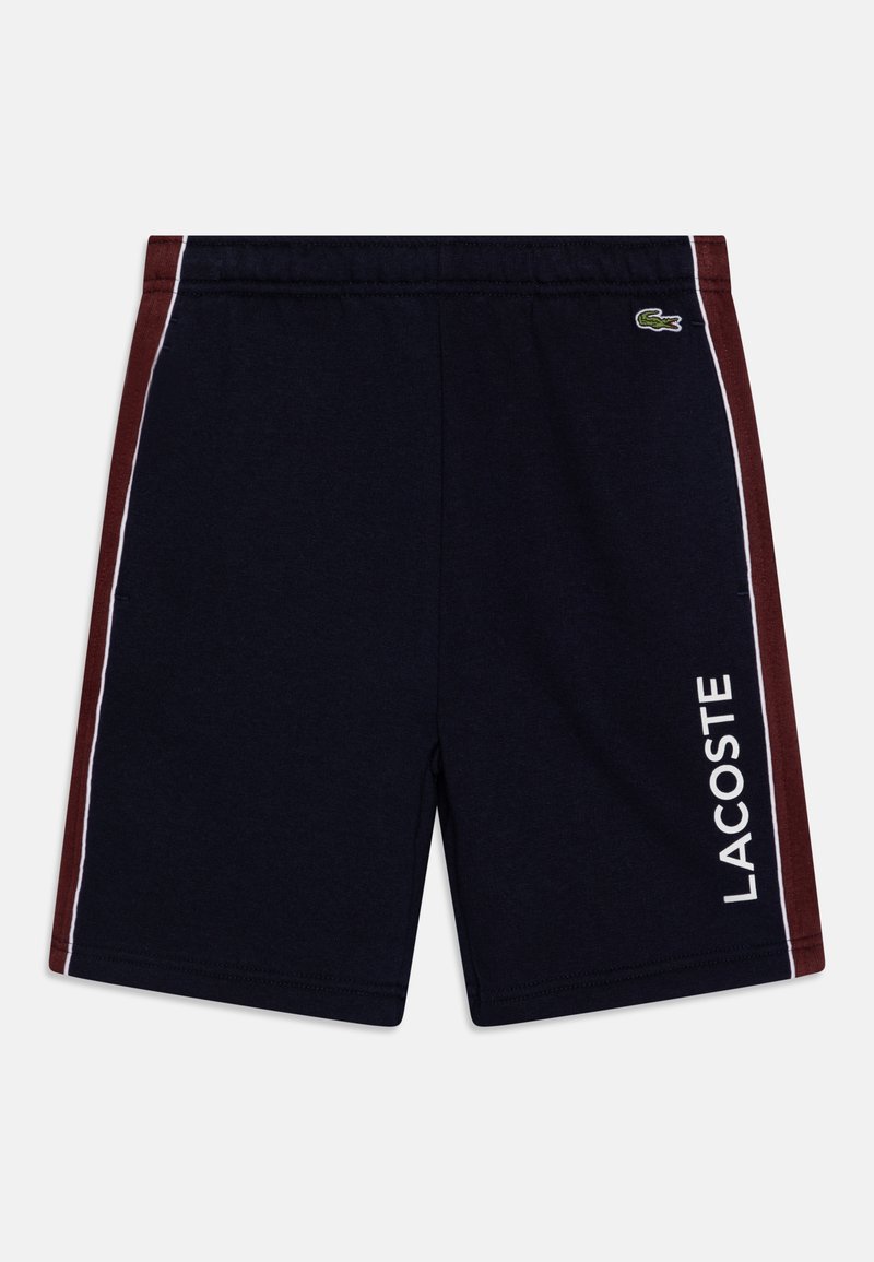 Tengerészkék rövidnadrág bordó oldalsó panelekkel, fehér díszítéssel és fehér "LACOSTE" logóval. Puha anyagból készült, elasztikus derékkal.