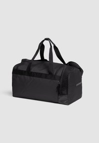 Bolsa de deporte negra hecha de material duradero, con una parte superior con cremallera, un panel lateral de malla y dos asas resistentes para un transporte fácil.