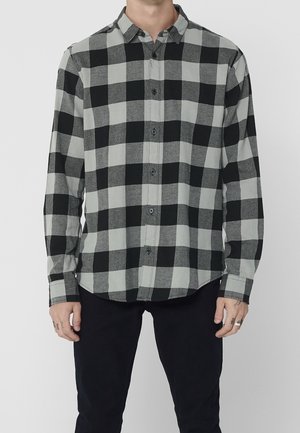 Chemise à manches longues à carreaux noirs et gris, fabriquée dans un tissu au toucher lisse, avec un col classique et une fermeture à boutons.