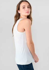Witte geribde tanktop met een aansluitend ontwerp, voorzien van brede schouderbanden en een ronde halslijn. Gladde stoftextuur, minimalistische stijl.