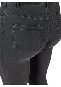 Musta farkkuhousut slim fit -mallissa, joissa on kaksi takataskua ja hienot ompeluyksityiskohdat. Kankaassa on sileä, hieman kulunut tuntuma.