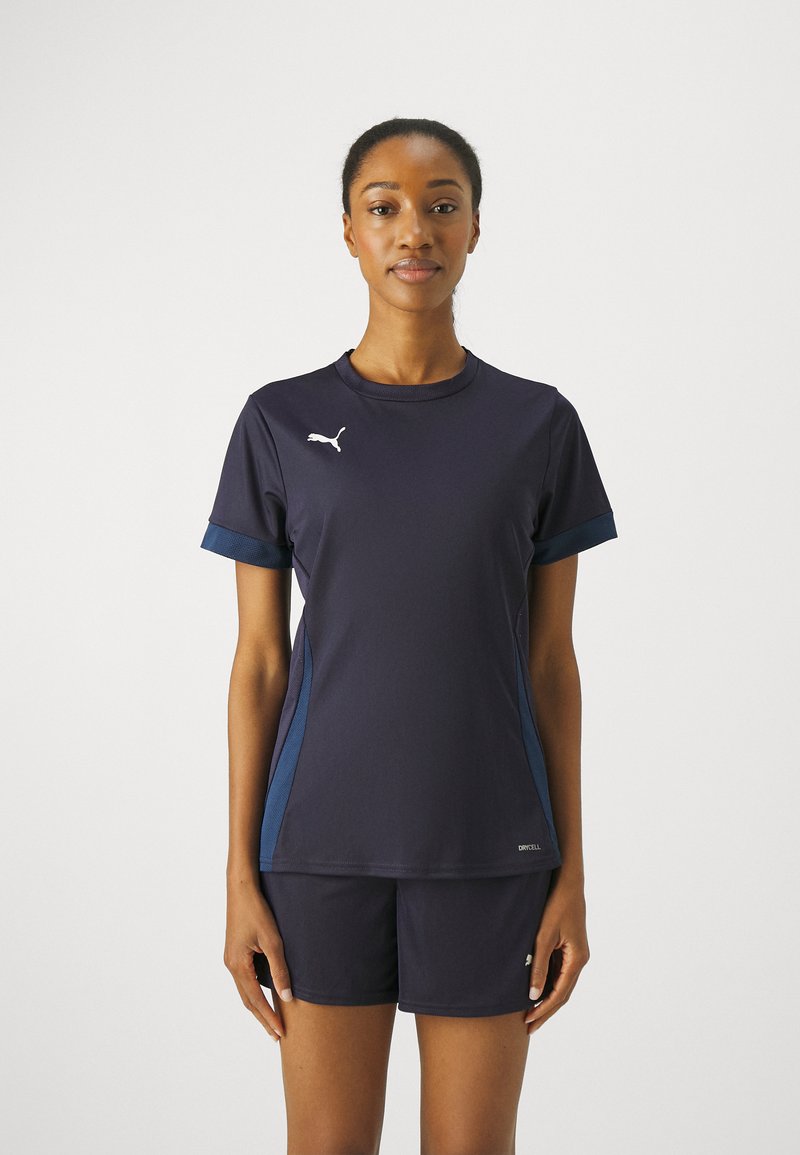 Marineblå atletisk top og shorts lavet af fugttransporterende stof, med lyseblå sidelænde og et hvidt logo på brystet.
