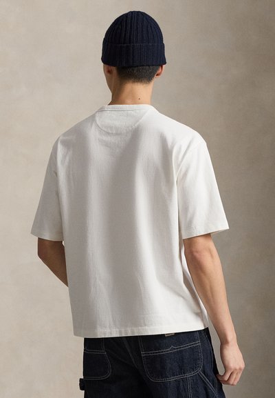 T-shirt blanc, ample, à manches courtes, en coton. Présente un col rond et une texture lisse, avec un dos uni.