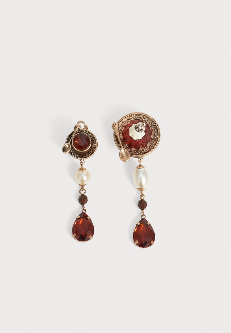 Boucles d'oreilles asymétriques de style vintage avec pierres précieuses rouges, perles, petites cuillères et détails métalliques dorés complexes sur fond blanc.