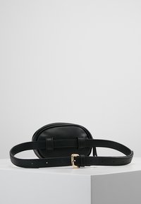 Czarna skórzana torba na pas o zaokrąglonym kształcie, z pozłacanymi okuciami i fakturowanym wykończeniem. Regulowany pasek dla dopasowania do indywidualnych potrzeb.