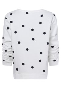 Sudadera blanca con grandes lunares negros, mangas largas con puños recogidos y un corte relajado. Cuello redondo sencillo y diseño simple.