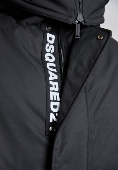 Black jacket featuring a prominent white logo tag, zip closure, and smooth texture, with metallic hardware accents and a hood.