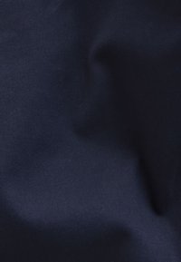 Dark blue fabric with subtle folds and a smooth texture, highlighting fine diagonal weave patterns.