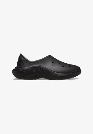 Chaussure de style sabot noire en matériau flexible, dotée de trous de ventilation et d'une semelle texturée avec de petits points surélevés pour une meilleure adhérence.