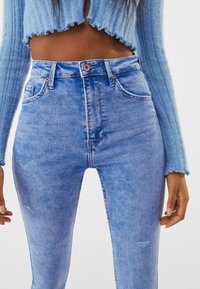 Lichtblauwe high-waisted jeans van denim, met een vervaagde was, vijf zakken en subtiele slijtage bij de knie.