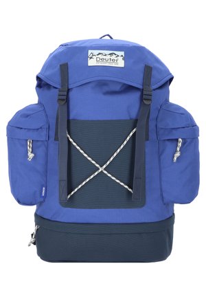 Blauer Stoffucksack mit einer oberen Klappe, zwei Seitentaschen, einem elastischen Kordelzug vorne und einem dunkelblauen Unterpaneel. Verfügt über verstellbare Träger und ein Logopatch.