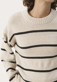 Pull en maille beige avec des rayures horizontales noires. Équipé d'un col côtelé et d'un motif texturé sur le corps et les manches.