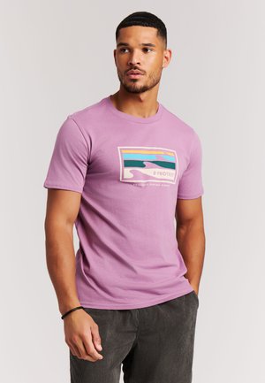 Lavendelkleurig katoenen T-shirt met een rechthoekige afbeelding met golven in blauw, groen, geel en roze. Rondhals en korte mouwen.