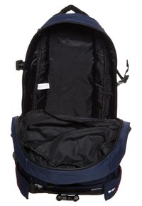 Mochila navy con un amplio compartimento principal, interior negro, correas ajustables y un bolsillo frontal. Cuenta con cremalleras y una textura de tela suave.