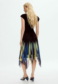 Pleated kleit, millel on sobiv must bodi ja gradient seelik, mis sisaldab siniseid ja kollaseid riba. Helk on asümmeetriline ja sisaldab läbipaistvaid detaile.