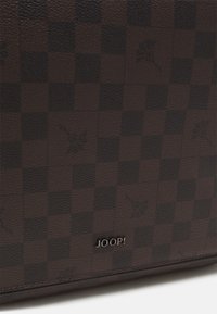 Producto de cuero marrón con un patrón de cuadros, que presenta sutiles motivos florales. Logotipo en relieve "JOOP!" en plata en la parte inferior.