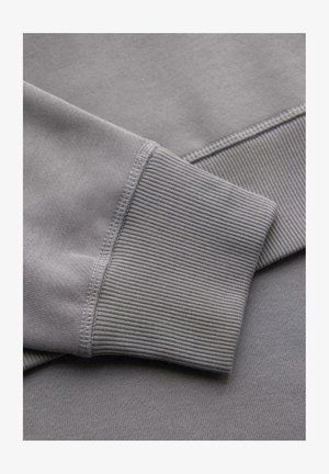 Harmaa college-paita, jossa on ribbikuvioinen hihansuu. Kankaan pinta on sileä ja pehmeällä ompelulla, ja siinä on yksivärinen kokonaisuus ilman kuvioita.